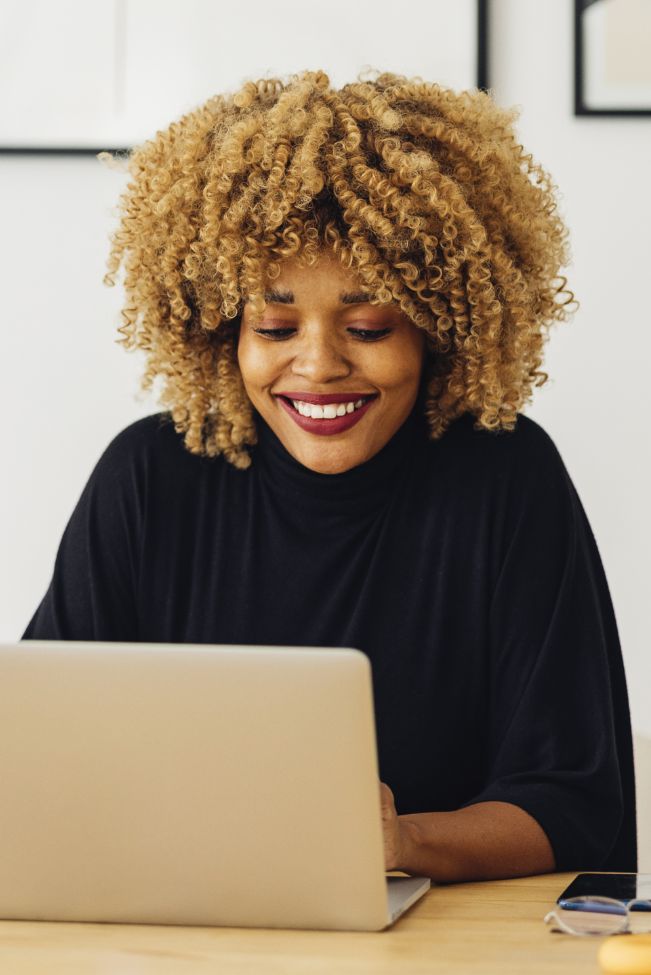 A smiling woman looking at a laptop