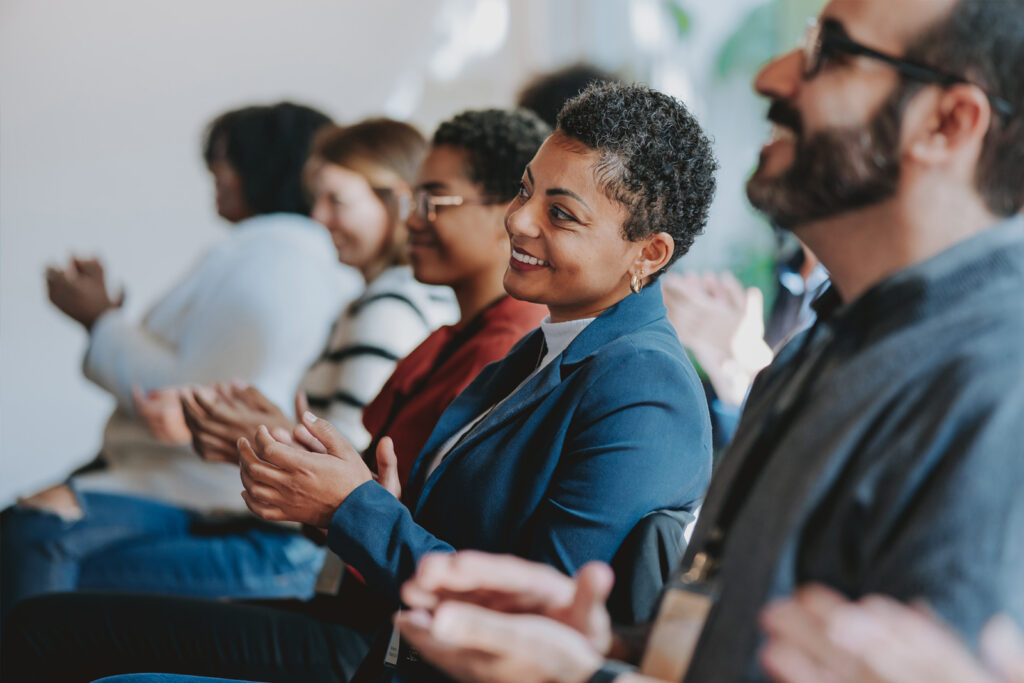 An engaged audience applauding at a corporate event engineered by the employee experience agency Ingenuity Design.