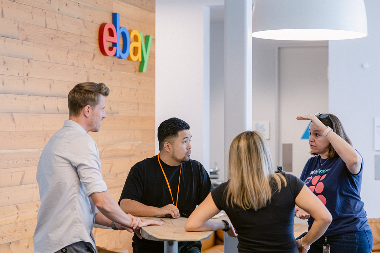 Four colleagues collaborating on materials together around an office desk for an eBay company program.
