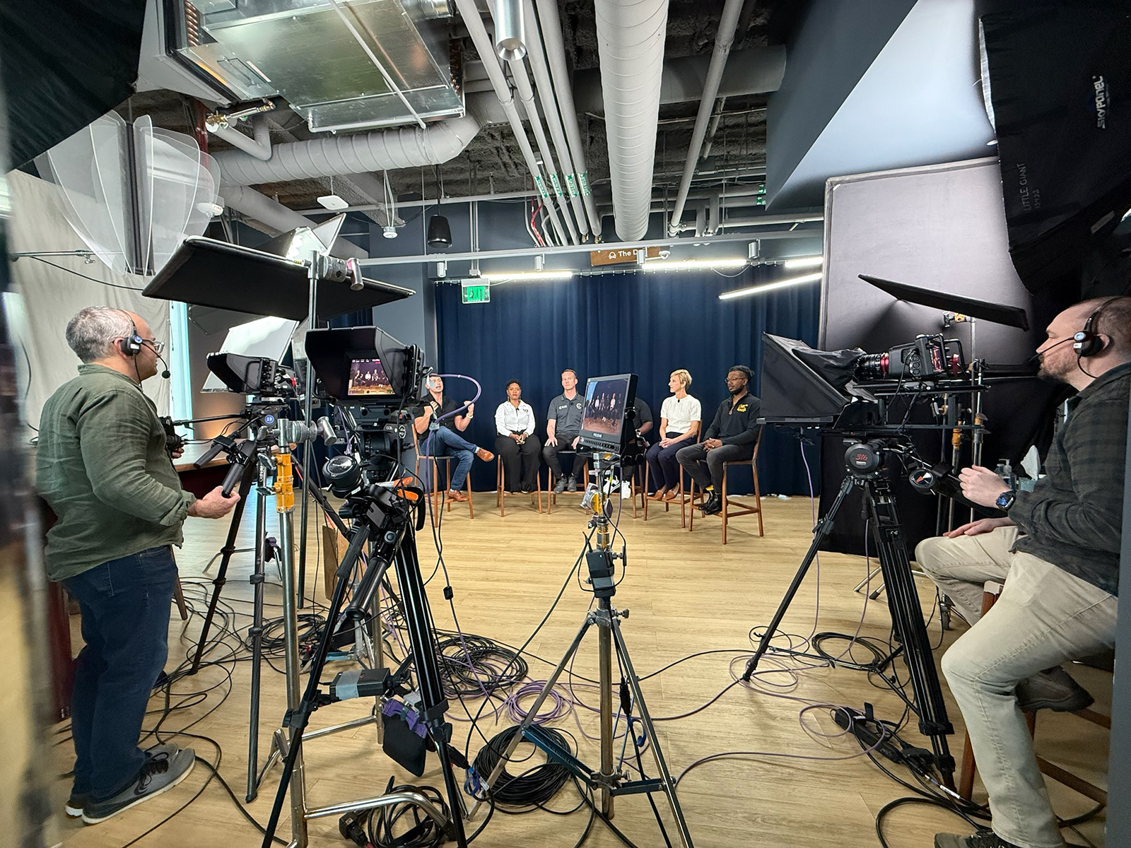 Behind-the-scenes view of production video cameras filming a live panel Q&A broadcast for the Thumbtack Pro Summit.