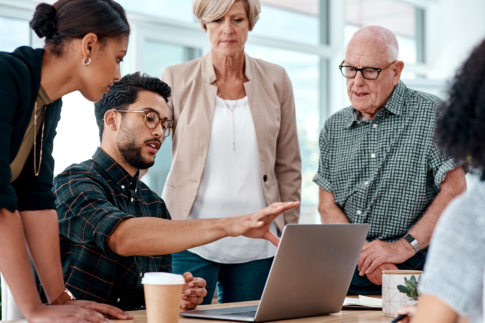 A professional gesturing to his laptop screen, walking his team through an EX strategy and roadmap.