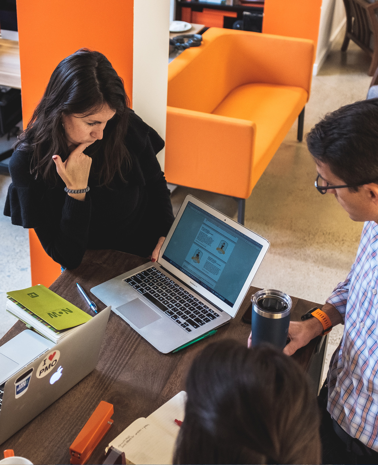 Two Ingenuity Design colleagues standing at a high-top table, reviewing a digital employee experience project on a laptop.