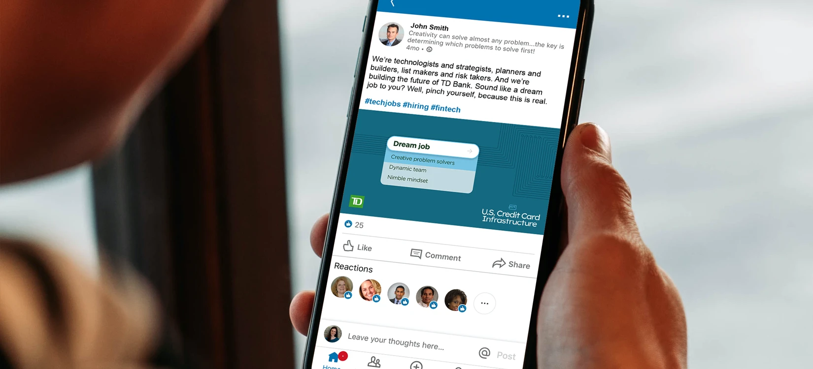 A hand holding a smartphone displaying a custom TD Bank LinkedIn post about a job opportunity.